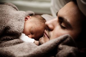Vater mit Neugeborenem in eine Decke gehüllt