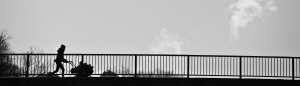 Frau mit Kinderwagen auf einer Brücke