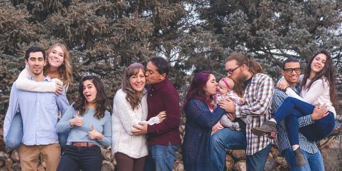 Familie mit steht vor einem Wald. Zu sehen sind alle Generationen von Jung bis alt.