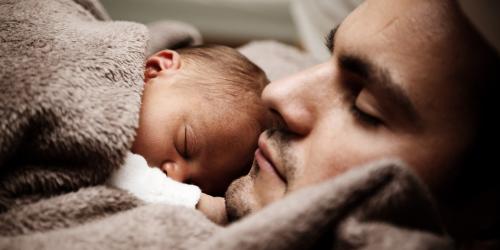 Vater mit Neugeborenem in eine Decke gehüllt